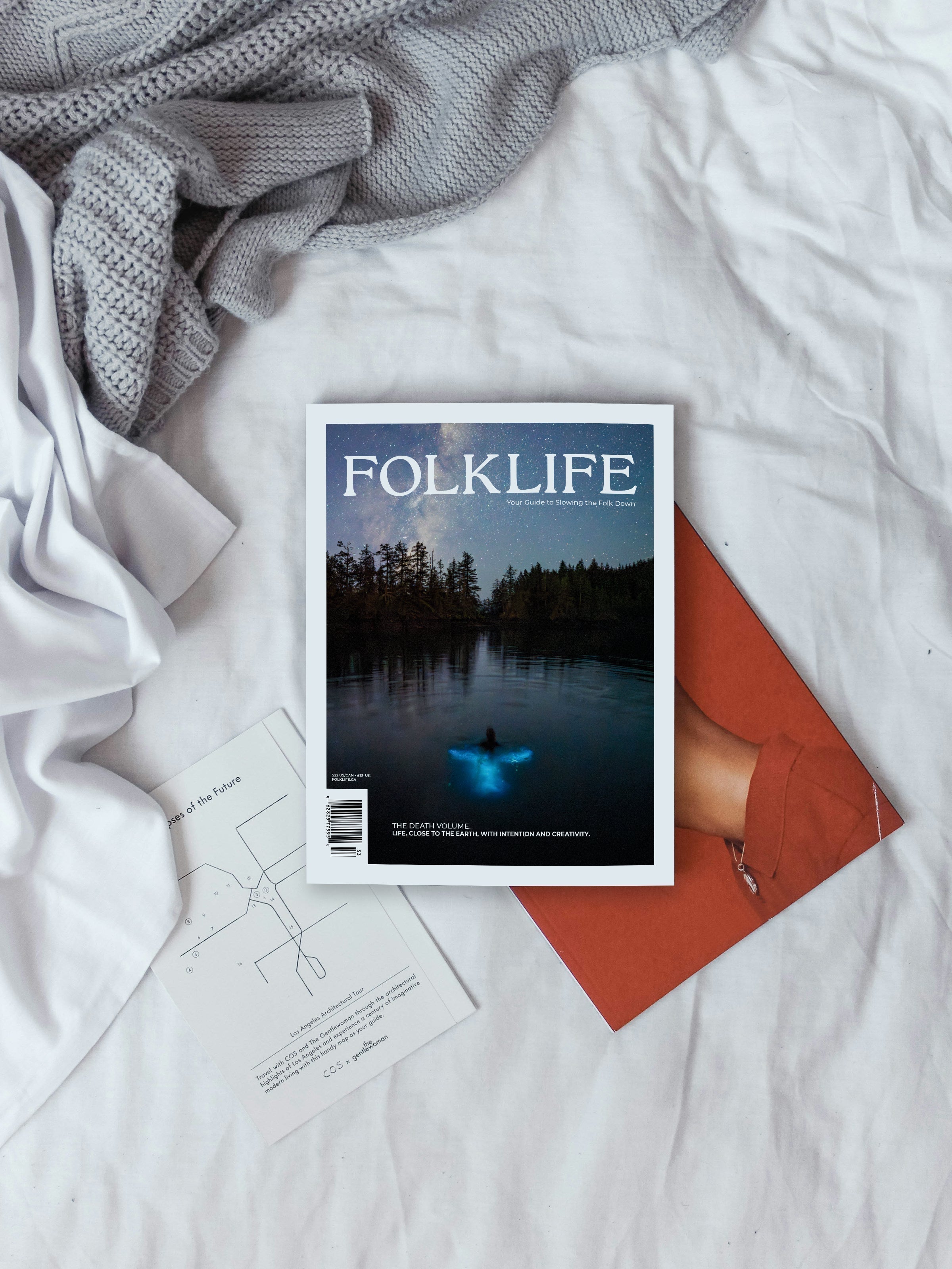 A FOLKLIFE magazine on a bed with other books, and sheets on the side.