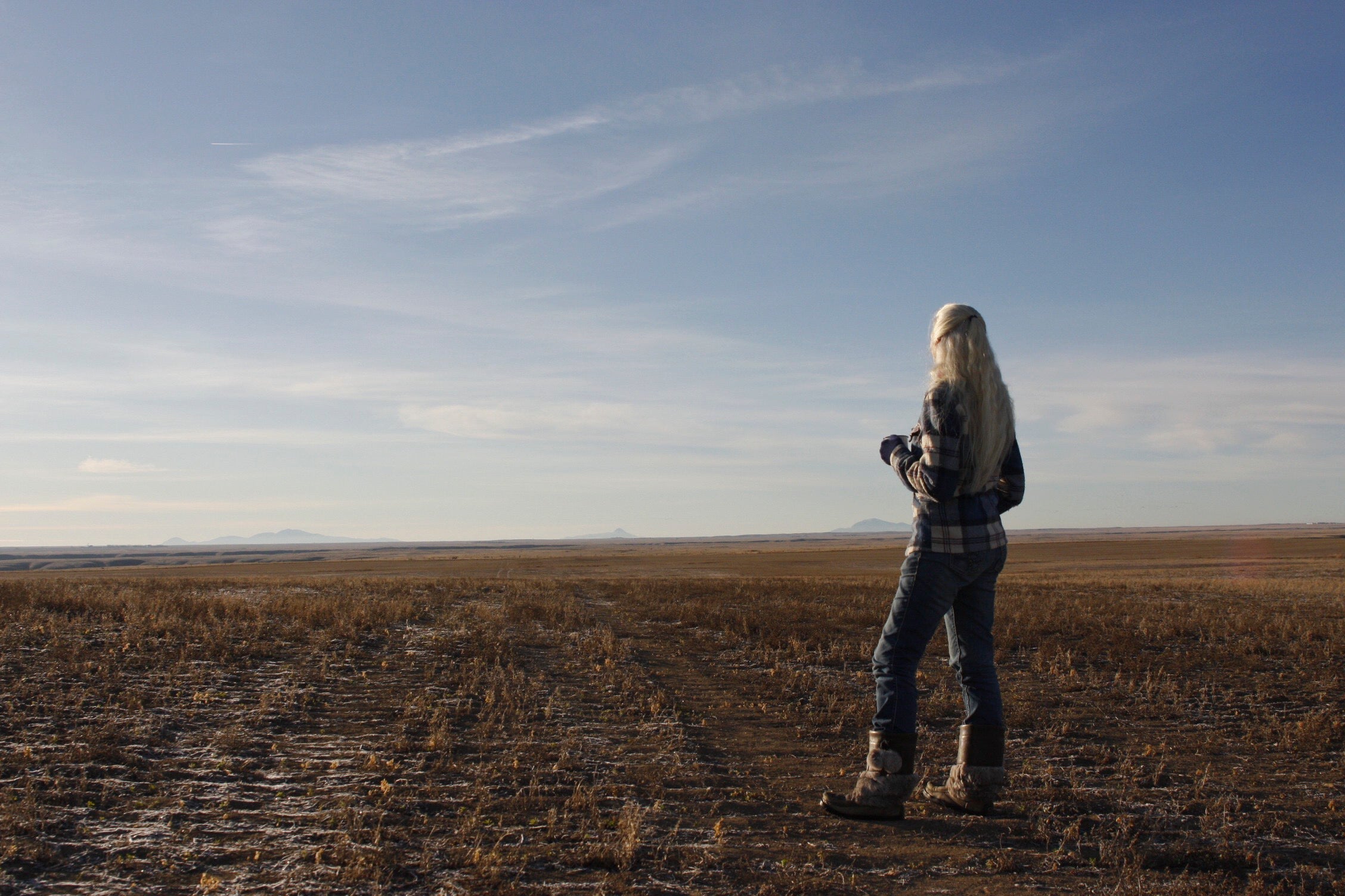 Woman standing alone in vast open prairie under a wide sky