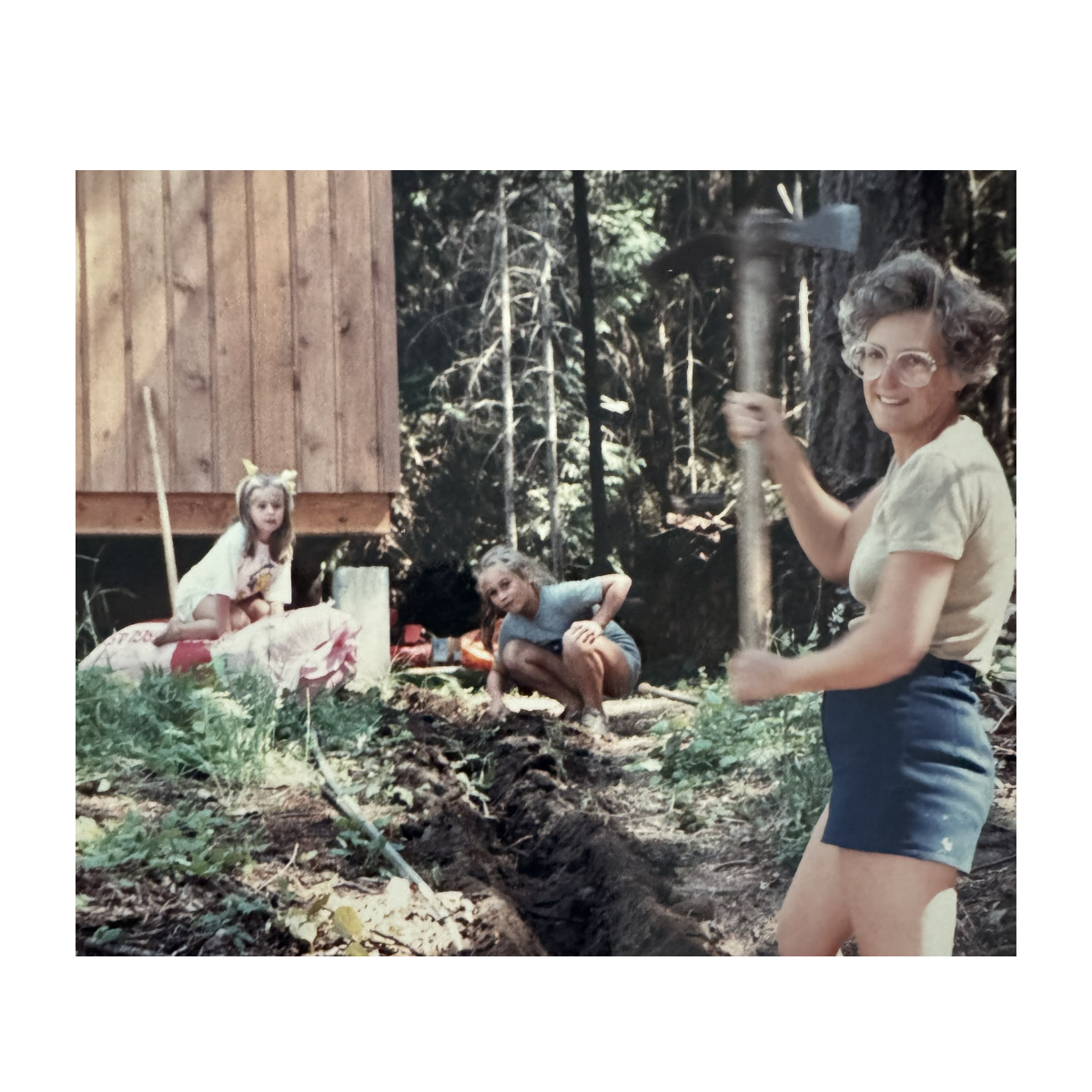 Woman holding an axe in a forest setting with two children.