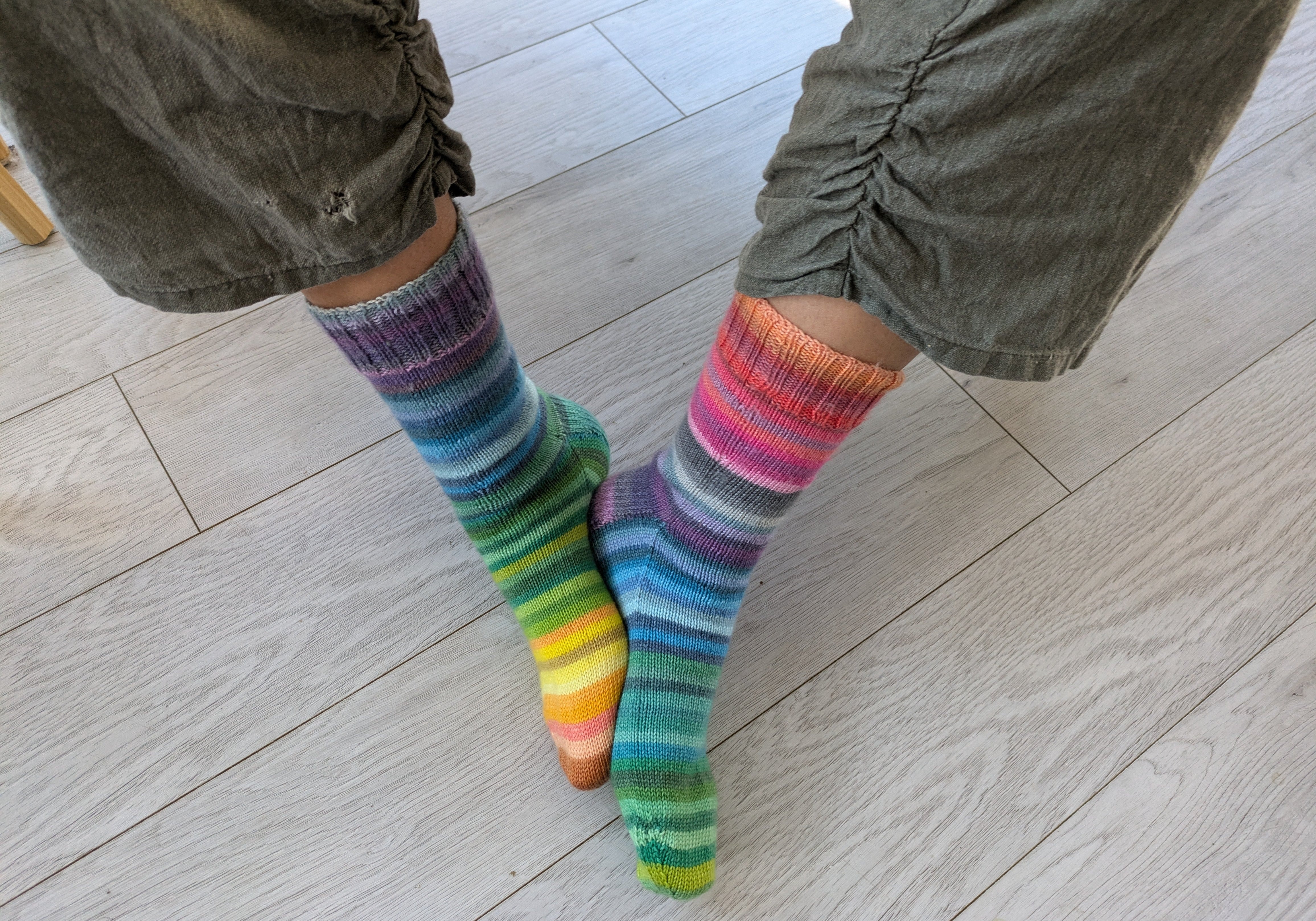 two legs in green pants with knitted rainbow coloured socks
