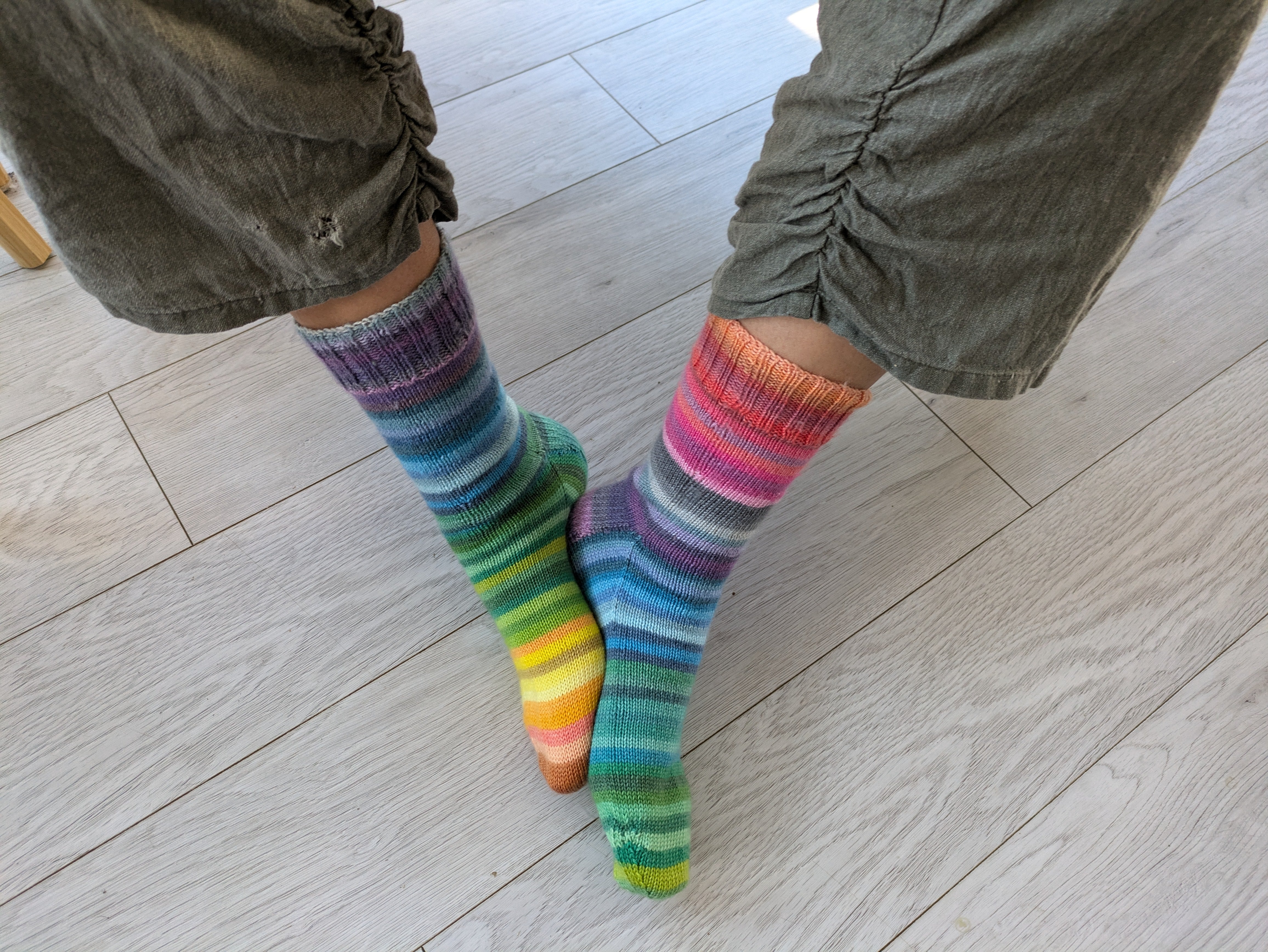 two legs in green pants with knitted rainbow coloured socks