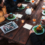 People enjoying a meal at a wooden table with decorative elements and drinks.