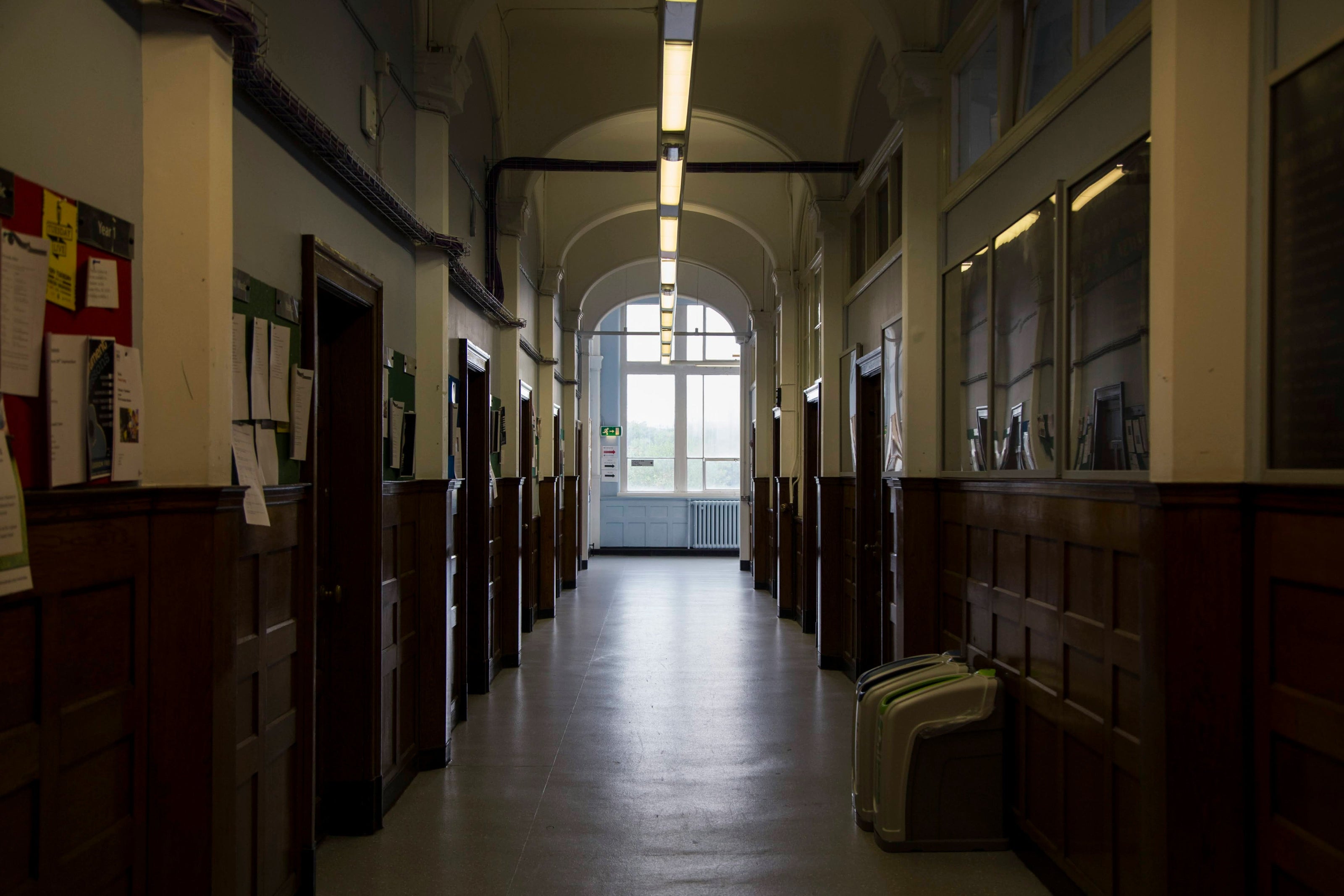 Long hallway with wooden lockers and a window at the end