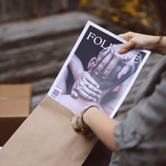 Person holding a FOLKLIFE magazine  and placing it into an envelope.
