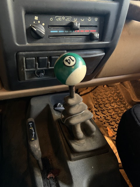 Car interior with a gear shift lever featuring a green and white ball.