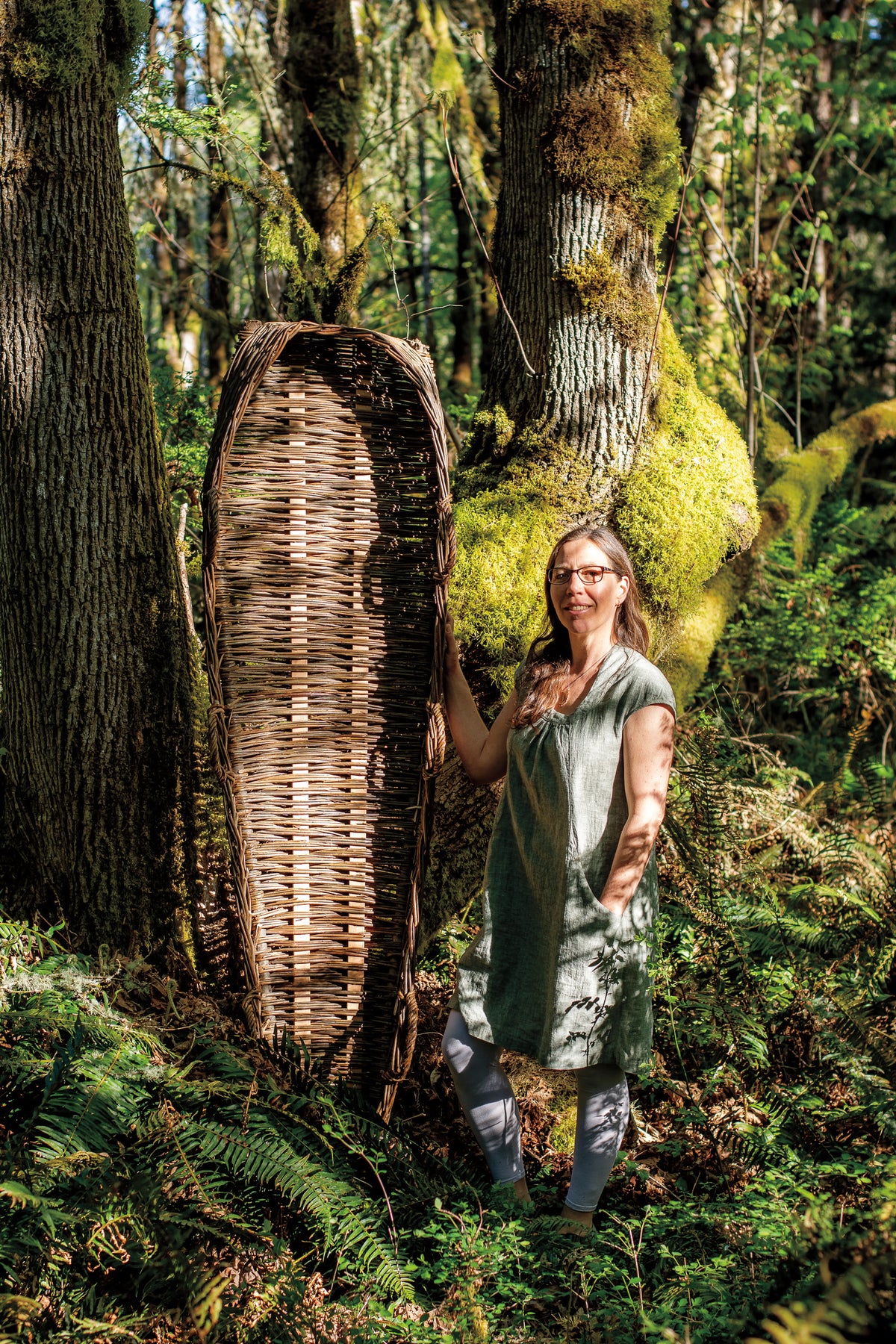 Catherine standing beside a handwoven willow casket in the forest