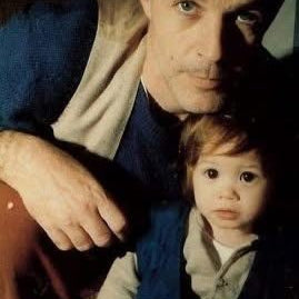 Man and child sitting together, with a close-up of their faces.