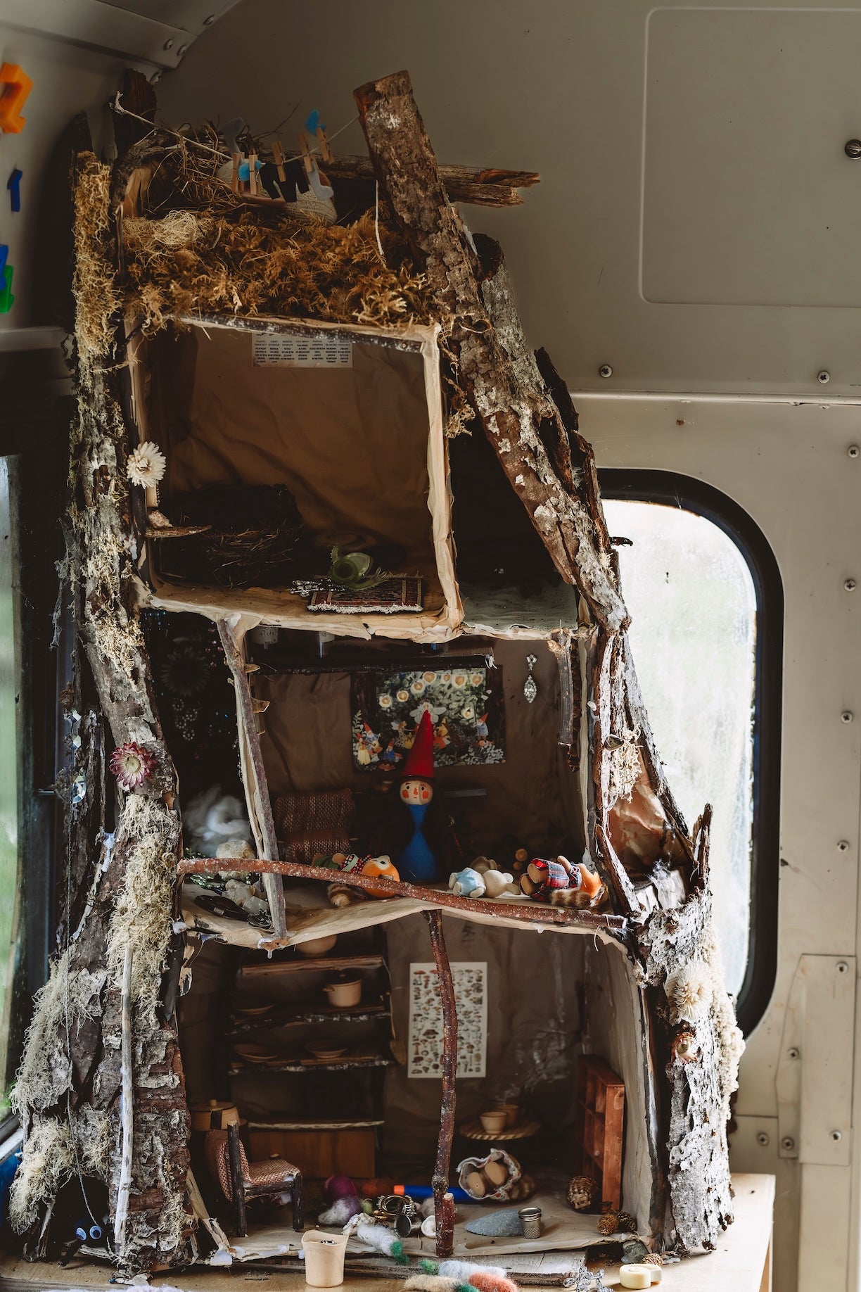 Rustic wooden dollhouse with various items inside a vehicle