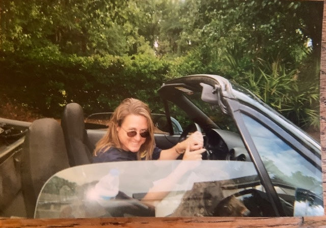 Person sitting in an open-top car with a scenic background