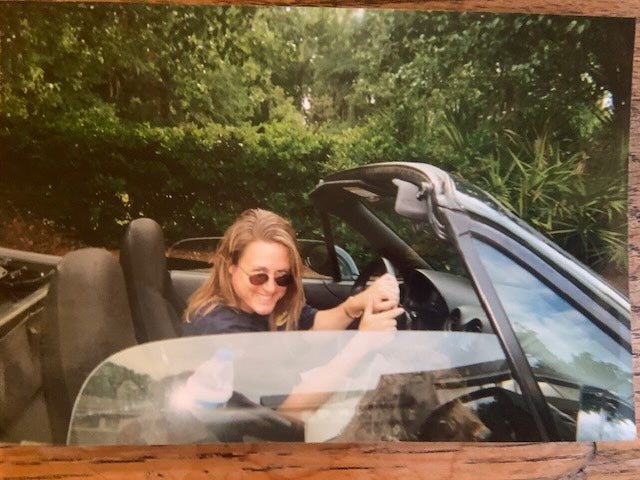 Person sitting in an open-top car with a scenic background