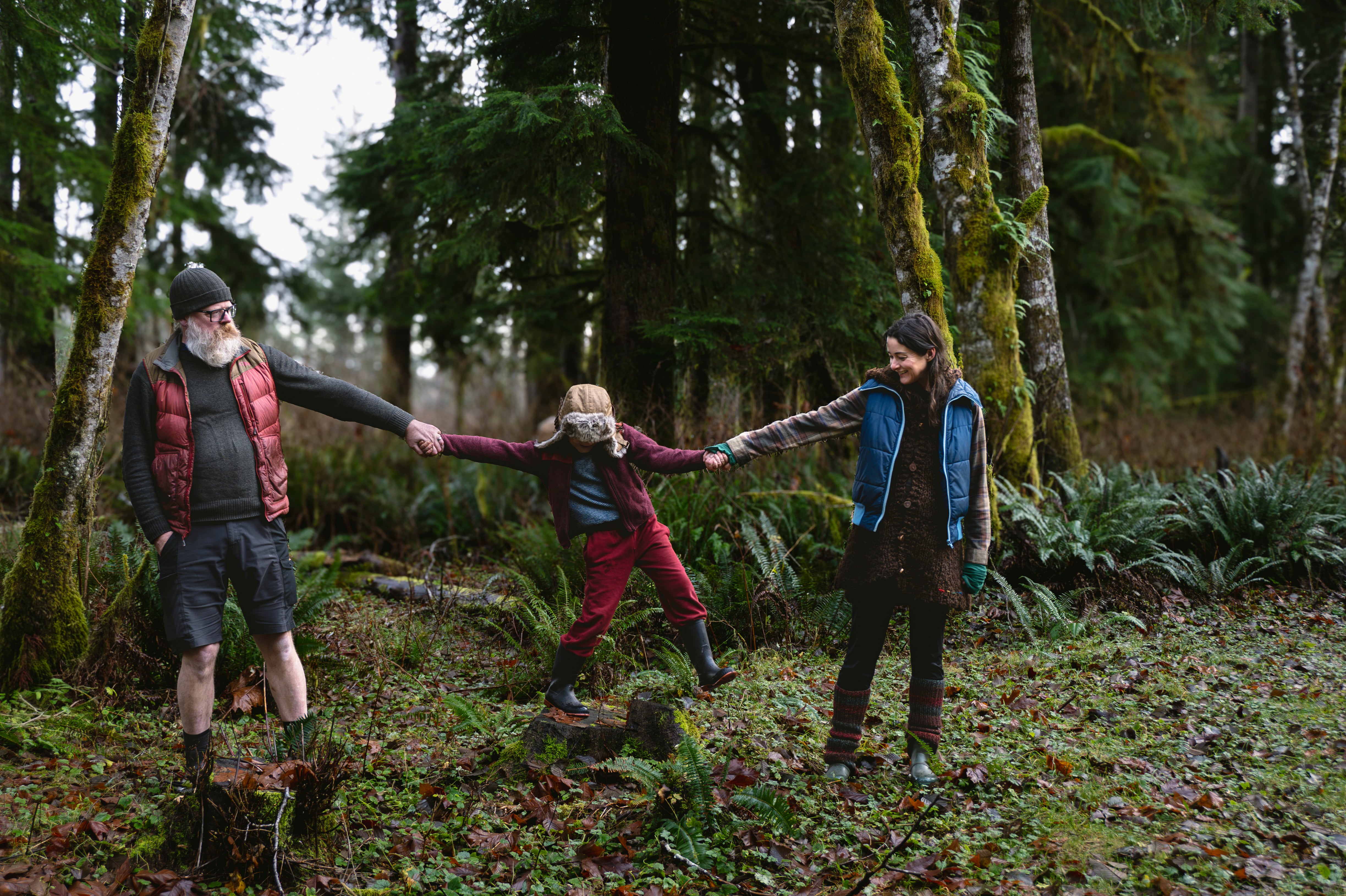 Three people holding hands in a forest setting